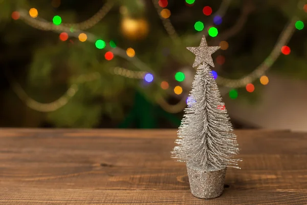 Decorated Christmas small silver tree on wooden table with glowing background — Stock Photo, Image