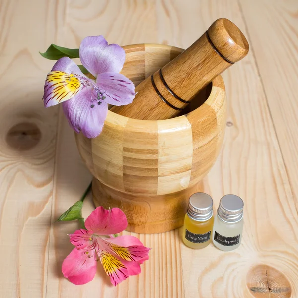 Hölzerner Bambus-Pounder mit Flaschen voller Öle und Blumen — Stockfoto