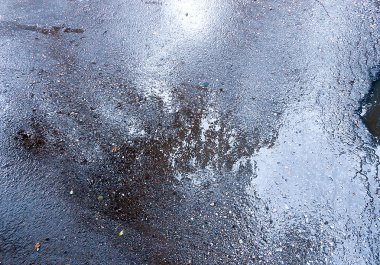 bir su birikintisine yansıyan ağaçları ile ıslak asfalt kaplama