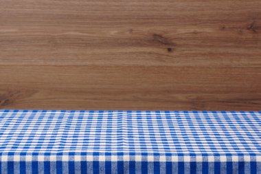 Boş bir tablo ile bir mavi kareli masa örtüsü. Ahşap arka plan.