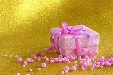 Sarı zemin üzerine hediye ile pembe kutu