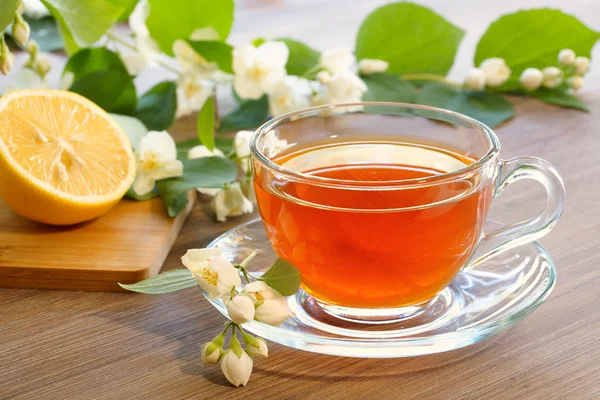 Tea with lemon and branches of a blooming jasmine — Stock Photo, Image