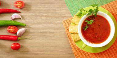 Ahşap bir masa üzerinde yeşil bir fincan domates çorbası. Üstten Görünüm.