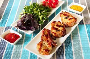Fried meat on a white plate and a plate with greens.