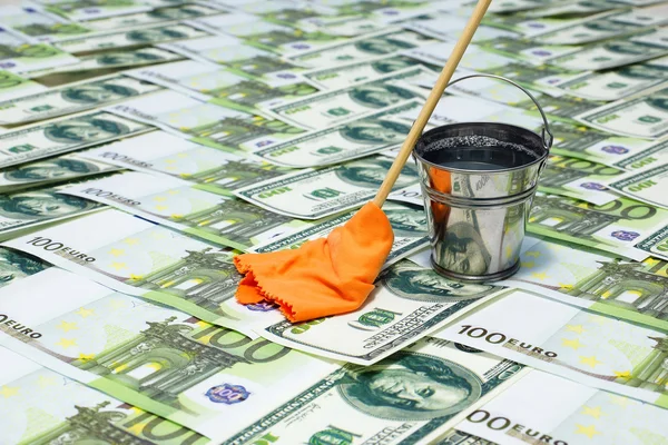 Laundering of money. Banknotes, a bucket of water and a mop with a rag — Stock Photo, Image