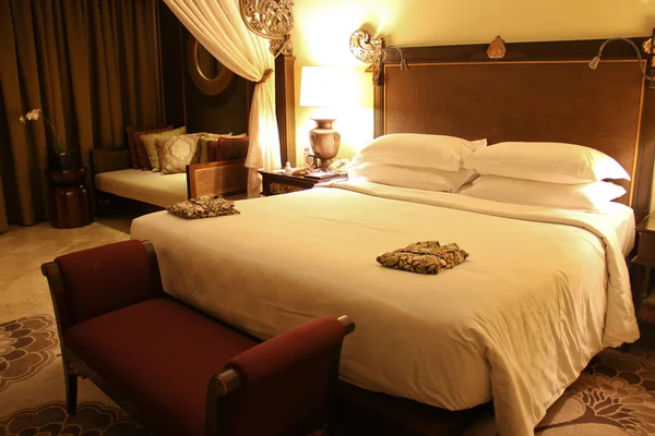 Yatakta iki bornoz ile otel odasında