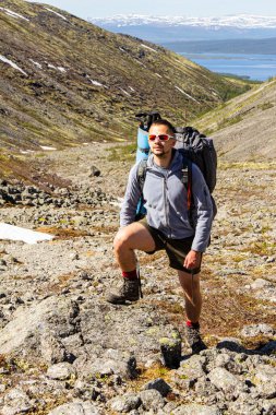 Büyük sırt çantaları ve yürüyüş direkleriyle Avrupalı erkek turist Khibiny dağlarının zirvesine tırmanır. Grup Yürüyüşçüleri yazın güneşli bir günde, Rusya ve Avrupa 'da spor yürüyüşü yapıyor.