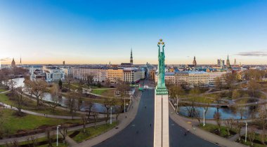 Sonbahar gündoğumunda arka planda eski bir kasabayla birlikte özgürlük anıtına muhteşem bir hava panoramik görünümü. Milda, özgürlük heykeli şehrin üzerinde üç altın yıldız tutuyor. Riga, Letonya, Avrupa.