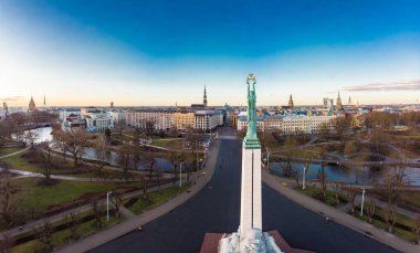 Sonbahar gündoğumunda arka planda eski bir kasabayla birlikte özgürlük anıtına muhteşem bir hava panoramik görünümü. Milda, özgürlük heykeli şehrin üzerinde üç altın yıldız tutuyor. Riga, Letonya, Avrupa.