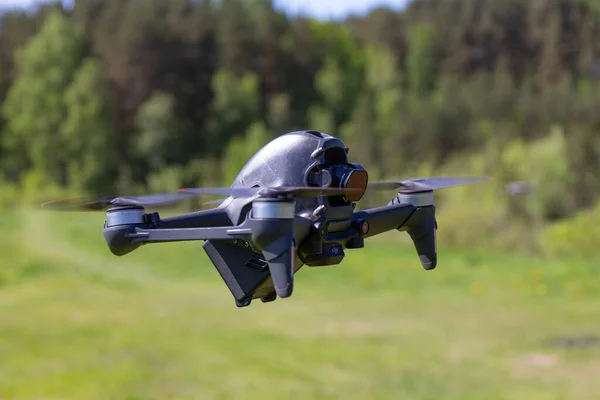 Moskou, 31 mei 2021: Een nieuwe DJI FPV drone vliegt op een zonnige dag op gras in Beckground. Bovenaanzicht. Hoofdloze quadcopter met digitale 4K 60 fps Hasselblad Camera en afstandsbediening Stockfoto