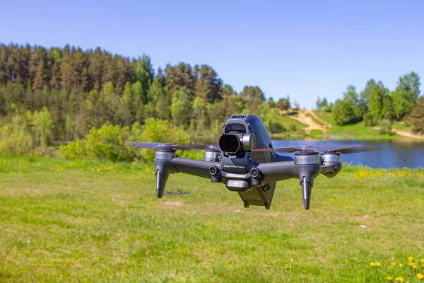 Moskou, 31 mei 2021: Een nieuwe DJI FPV drone vliegt op een zonnige dag op gras in Beckground. Bovenaanzicht. Hoofdloze quadcopter met digitale 4K 60 fps Hasselblad Camera en afstandsbediening Rechtenvrije Stockfoto's