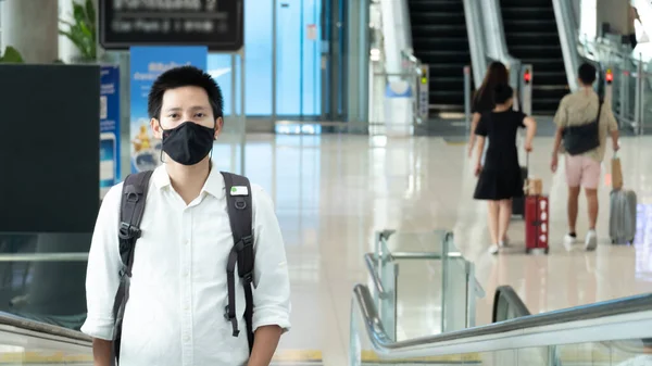 Man with luggage in airport terminal. Social distancing, International airport, on holiday, Corona virus, passenger wearing protective mask, after Covid-19, outbreak, Finding solitude