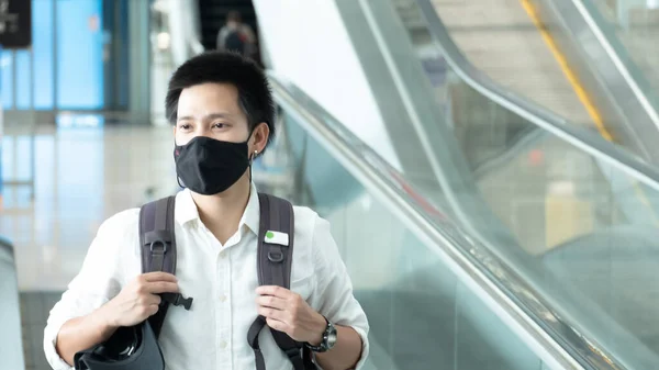 Man with luggage in airport terminal. Social distancing, International airport, on holiday, Corona virus, passenger wearing protective mask, after Covid-19, outbreak, Finding solitude