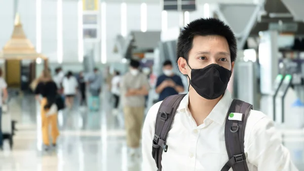 Man with luggage in airport terminal. Social distancing, International airport, on holiday, Corona virus, passenger wearing protective mask, after Covid-19, outbreak, Finding solitude