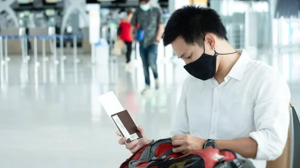 Man with luggage in airport terminal. Social distancing, International airport, on holiday, Corona virus, passenger wearing protective mask, after Covid-19, outbreak, Finding solitude