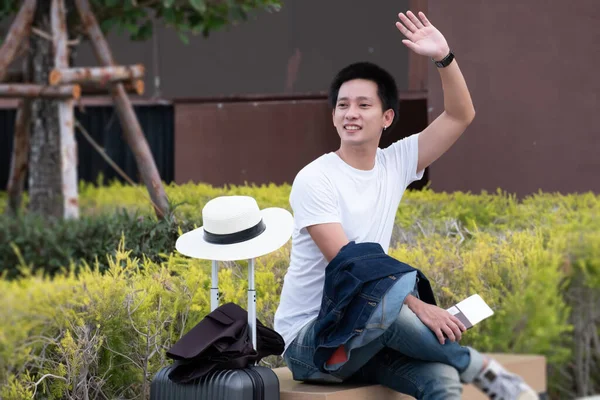 Happy Asian man with luggage or suitcase ready to travel for his holidays, traveller male casual on vacation concept.