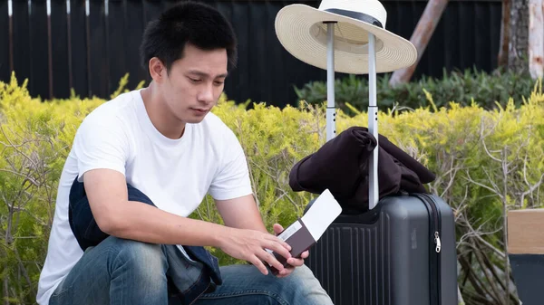 Happy Asian man with luggage or suitcase ready to travel for his holidays, traveller male casual on vacation concept.