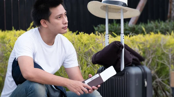 Happy Asian man with luggage or suitcase ready to travel for his holidays, traveller male casual on vacation concept.