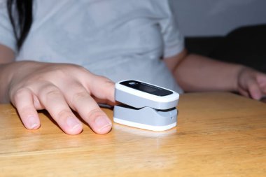 Beyaz arka planda işaret parmağında nabız oksimetresi var. Kan oksijeni ve nabız ölçümü. Yukarıdan bak. Akciğer hastalığı. Kavram