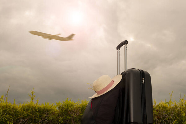 Concept of summer traveling or vacation with suitcase on blur airplane background