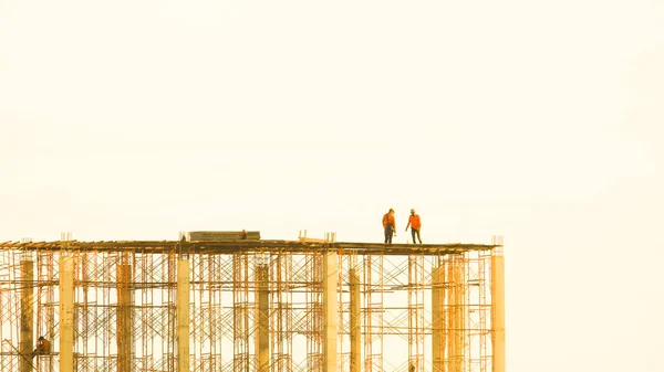 Construction of new residential high-rise buildings. Against the background of sunset sky. Working at height, Worker as in construction. technician and mechanic working on scaffolding or high crane.