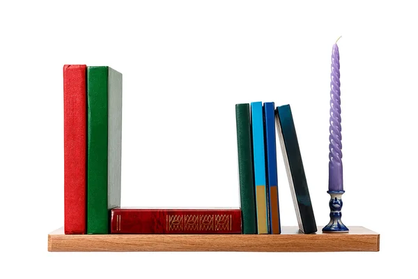 Свічка і кілька книг на полиці — стокове фото