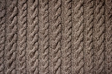 Textile background brown crochet close-up. Knitted needlework with aran pattern 