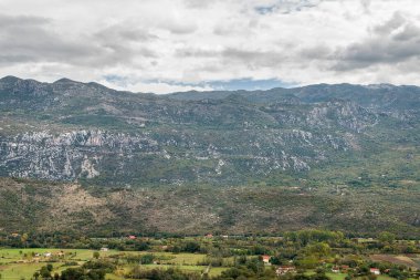 Dağlarla çevrili bir vadideki köy. Bulutlu havada dağlı manzara.