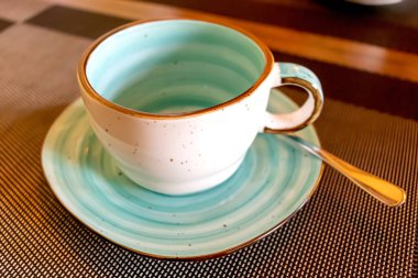 Boş su bardağı ve çay kaşığı servis edilen kafe masası.