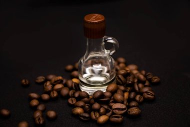 Büyük kahverengi kahve çekirdekleri ve beyaz arka planda vanilyalı bir şişe.