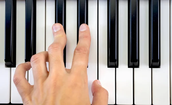 Fingers play chords on piano keys playing synthesizer pianist music hobby top view.