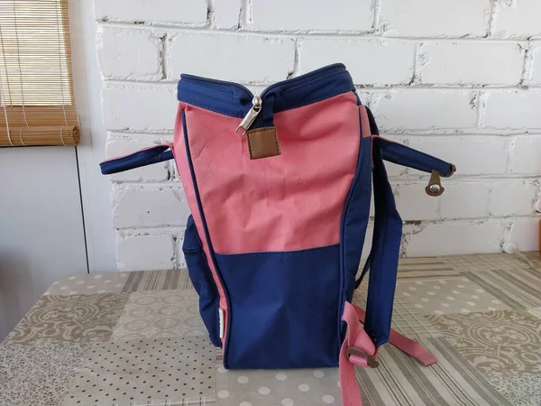 Açık mavi ve pembe sırt çantası masada, izole edilmiş.