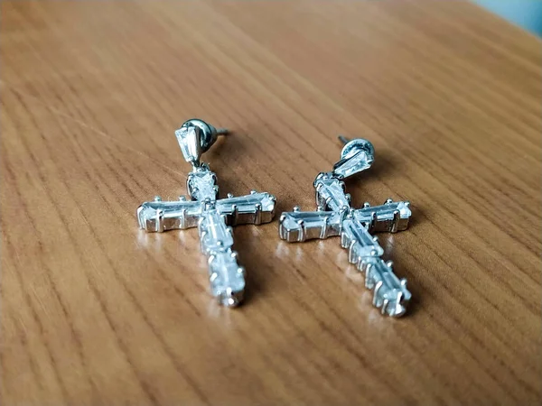 Earrings in the form of a cross on a wooden table