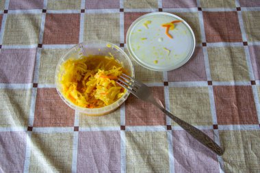 Sarı lahana turşulu konteynır masanın üstünde ve çatalın yanında.