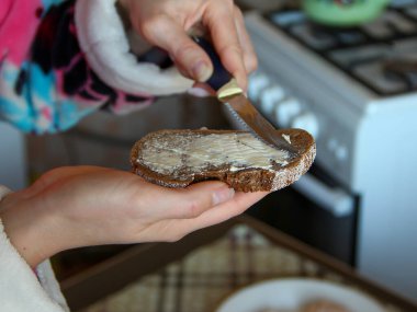 Kadın eli sandviç yapar, kahverengi ekmeğe tereyağı sürer. Yakın çekim.