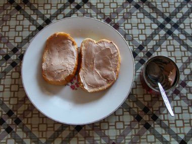 Tabakta ciğer ezmeli iki sandviç ve bir kavanoz böreğin yanında.
