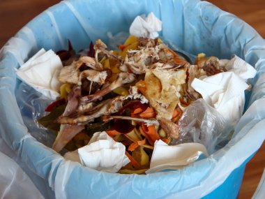 Mutfaktaki çöp tenekesinde yemek artıkları var.