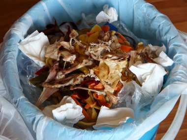 Mutfaktaki çöp tenekesinde yemek artıkları var.