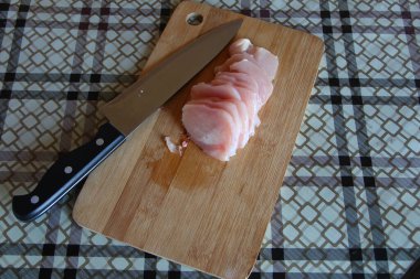 Kesme tahtasında bıçakla kesilmiş tavuk göğsü.