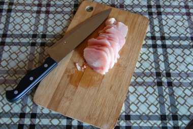 Kesme tahtasında bıçakla kesilmiş tavuk göğsü.