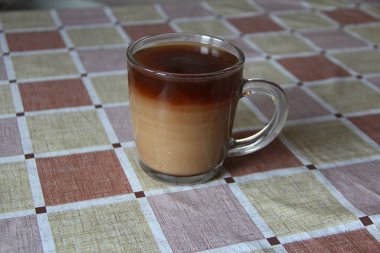 Şeffaf kahve kupası sütlü, içkinin rengi katmanlı olarak değişiyor.