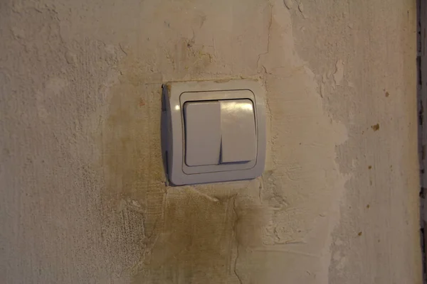 Dirty white light switch with dirty handprints on the dirty white wall background