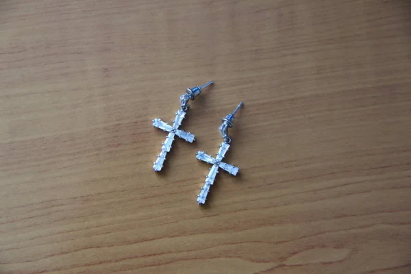 Earrings in the form of a cross on the wooden table