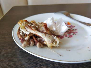 Yemekten sonra kirli tabakta tavuk kemikleri.