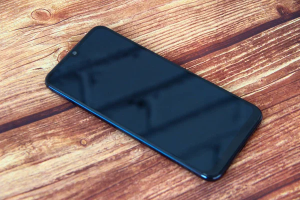 Ahşap arka planda siyah ekranlı akıllı telefon