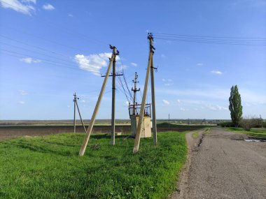 Kırsalda eski trafo kutusu ve elektrik hatları var.