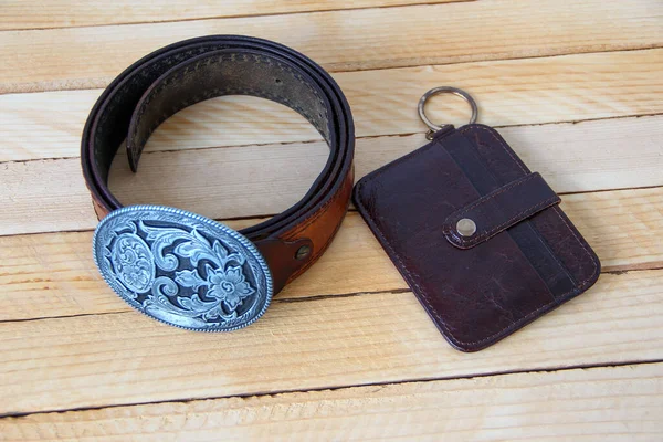 Leather cowboy belt and leather wallet on a wooden background