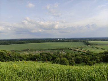 Manzara - vadi, tarlalar, orman ve gökyüzü bulutlarda