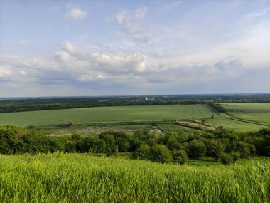 Manzara - vadi, tarlalar, orman ve gökyüzü bulutlarda