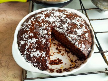 Tek dilimsiz ev yapımı çikolatalı turta üzerine pudra şekeri serpilmiş.